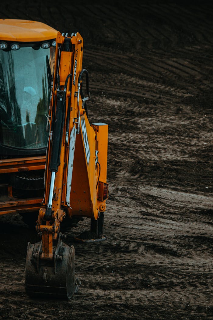 Close-up of a yellow excavator on a construction site with muddy terrain.